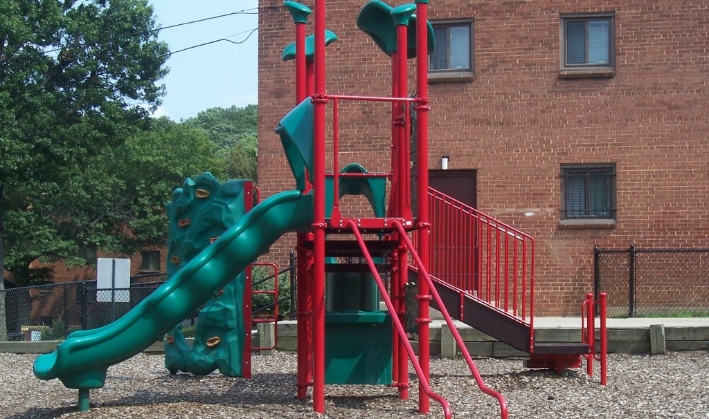 A playground with a green slide and red structure.